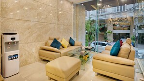 A modern living room with two sofas, a glass coffee table, and a water dispenser. - Celina Hotel & Apartment (Da Nang)