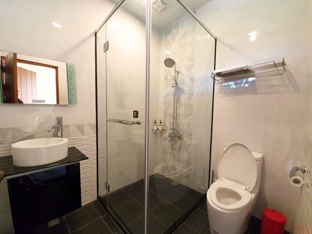 Een moderne badkamer met een douchecabine van glas, een wit wastafelmeubel en een toilet.