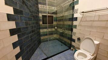 Une salle de bain avec une douche à parois de verre, des toilettes et un lavabo.