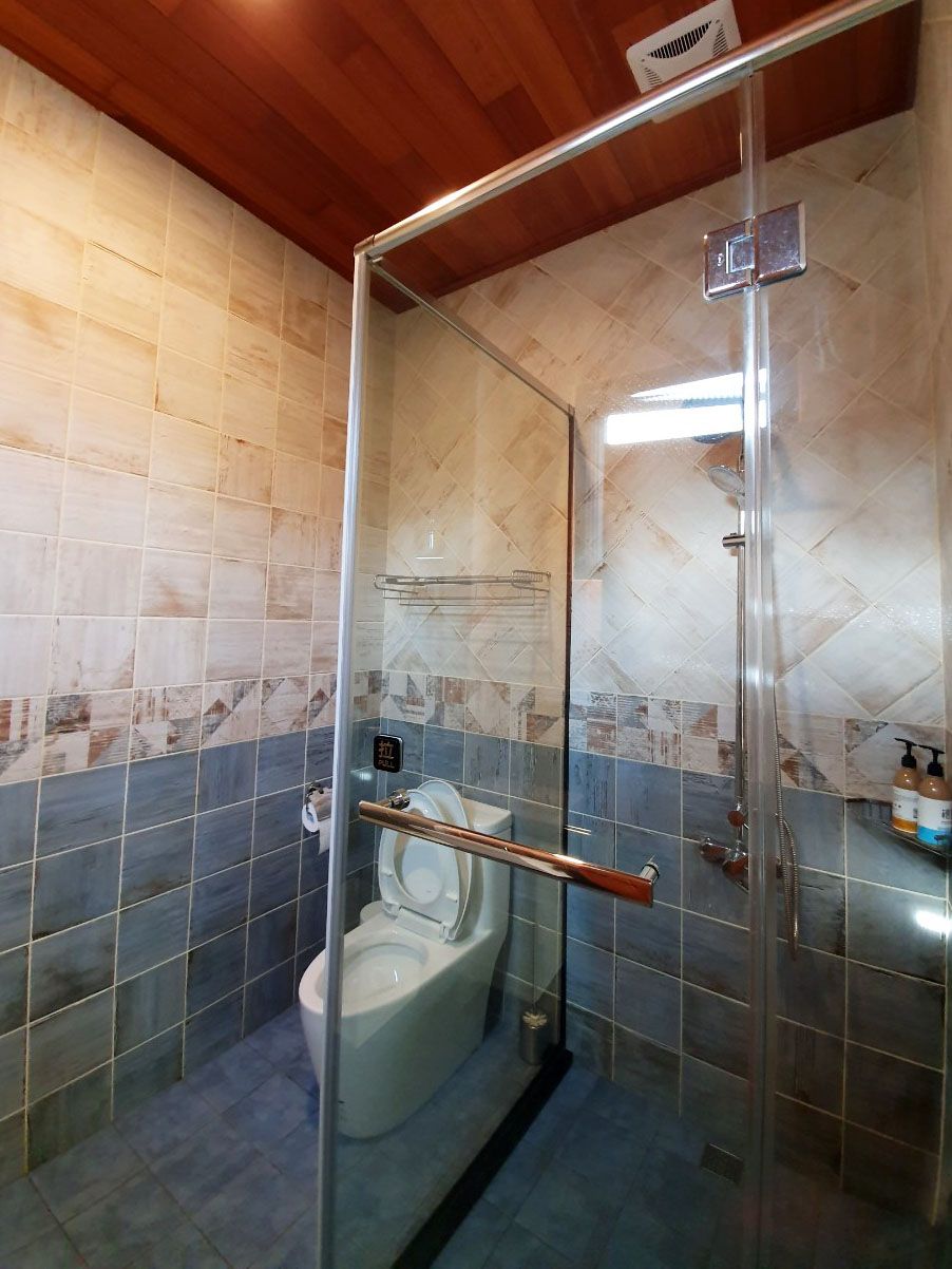 A bathroom with a glass-enclosed shower, a toilet, and a sink.