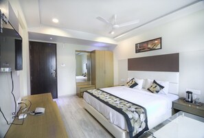 Una habitación de hotel con cama, mesita de noche y ventilador de techo.