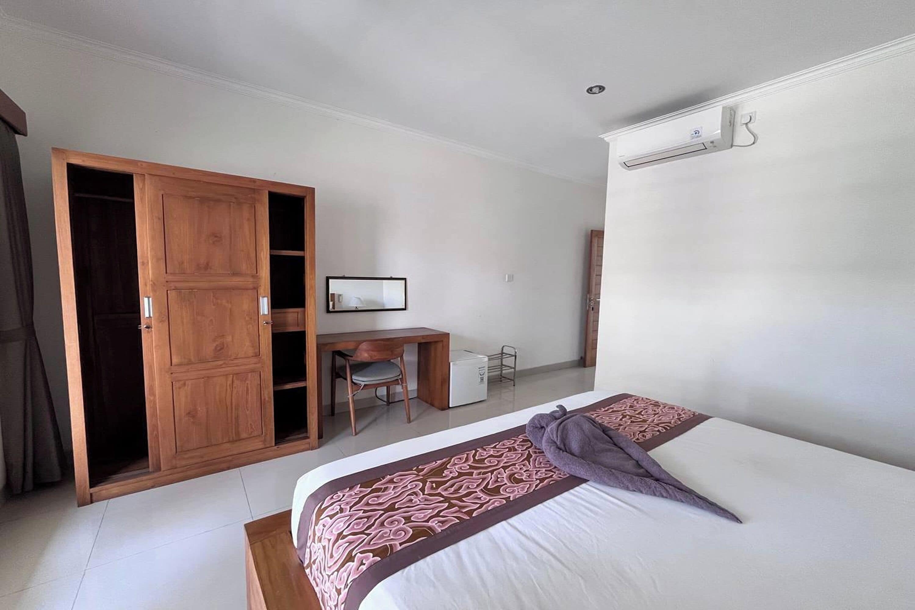 Een slaapkamer met een bed, een bureau, een stoel en een kledingkast.