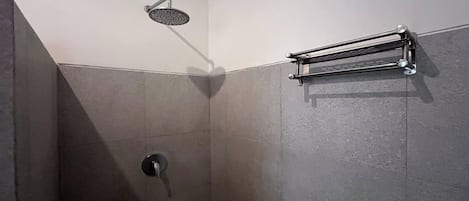 Een douche met een handdouche, een handdoekhouder en een muurkraan.