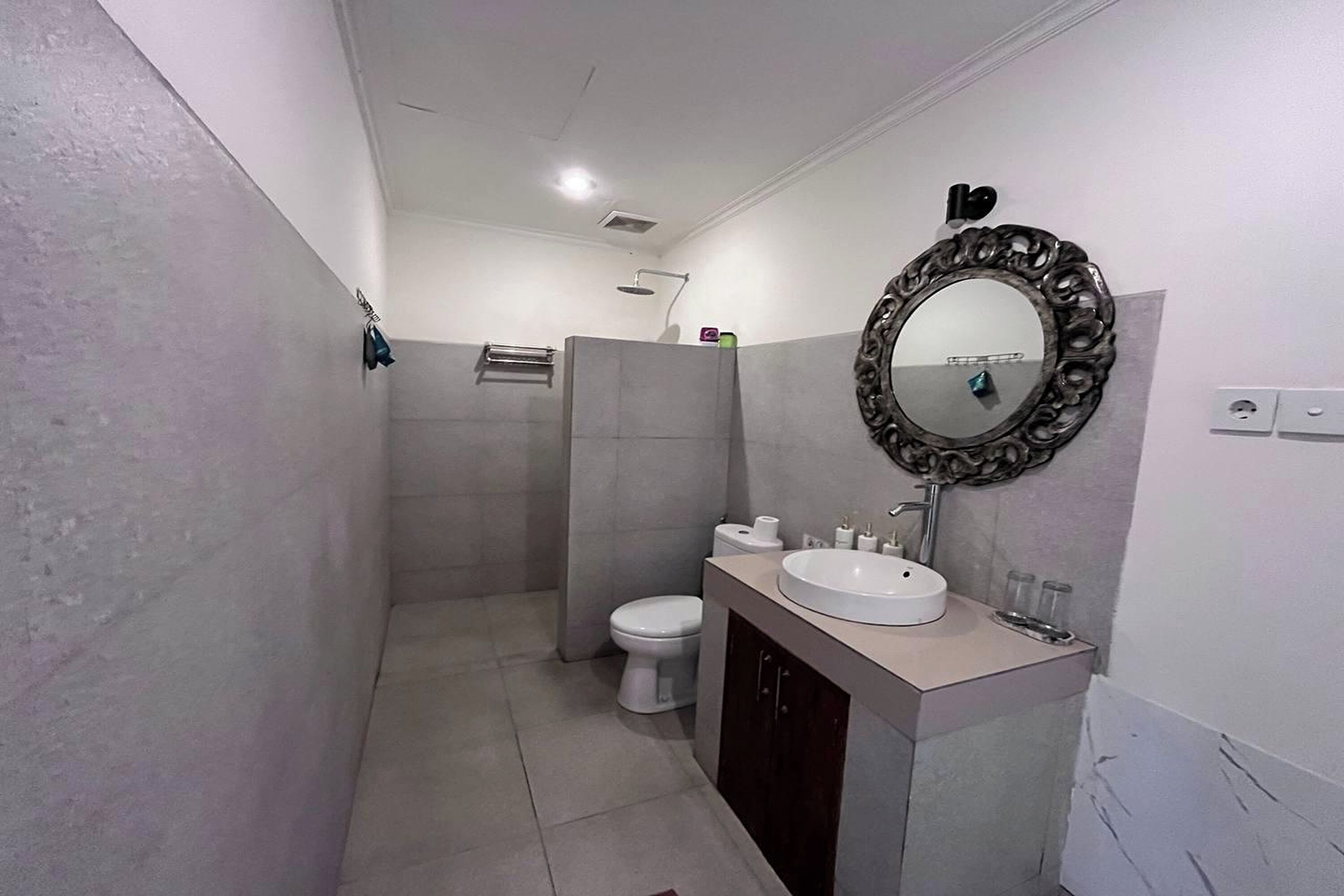 A bathroom with a shower, toilet, sink, and mirror.