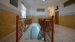 Amplio espacio interior con una escalera de cristal central, un ventilador de techo y azulejos decorativos en las paredes.