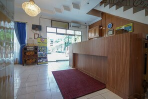 A hotel reception area with a wooden reception desk, a red carpet, and a chandelier. - Super OYO 1173 Hotel Shofa Marwah (Palembang)