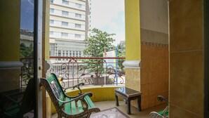 Un balcón con vista a un edificio, una baranda metálica y un banco.