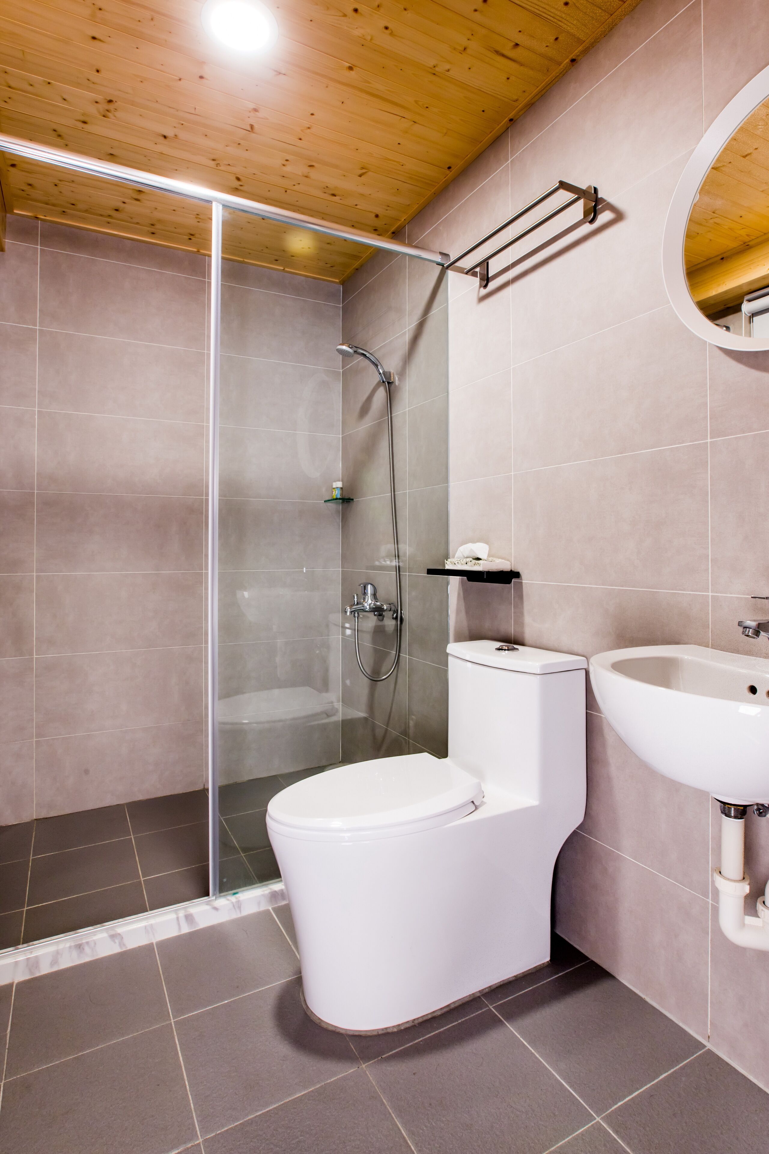 A modern bathroom with a glass-enclosed shower, a white toilet, and a sink.