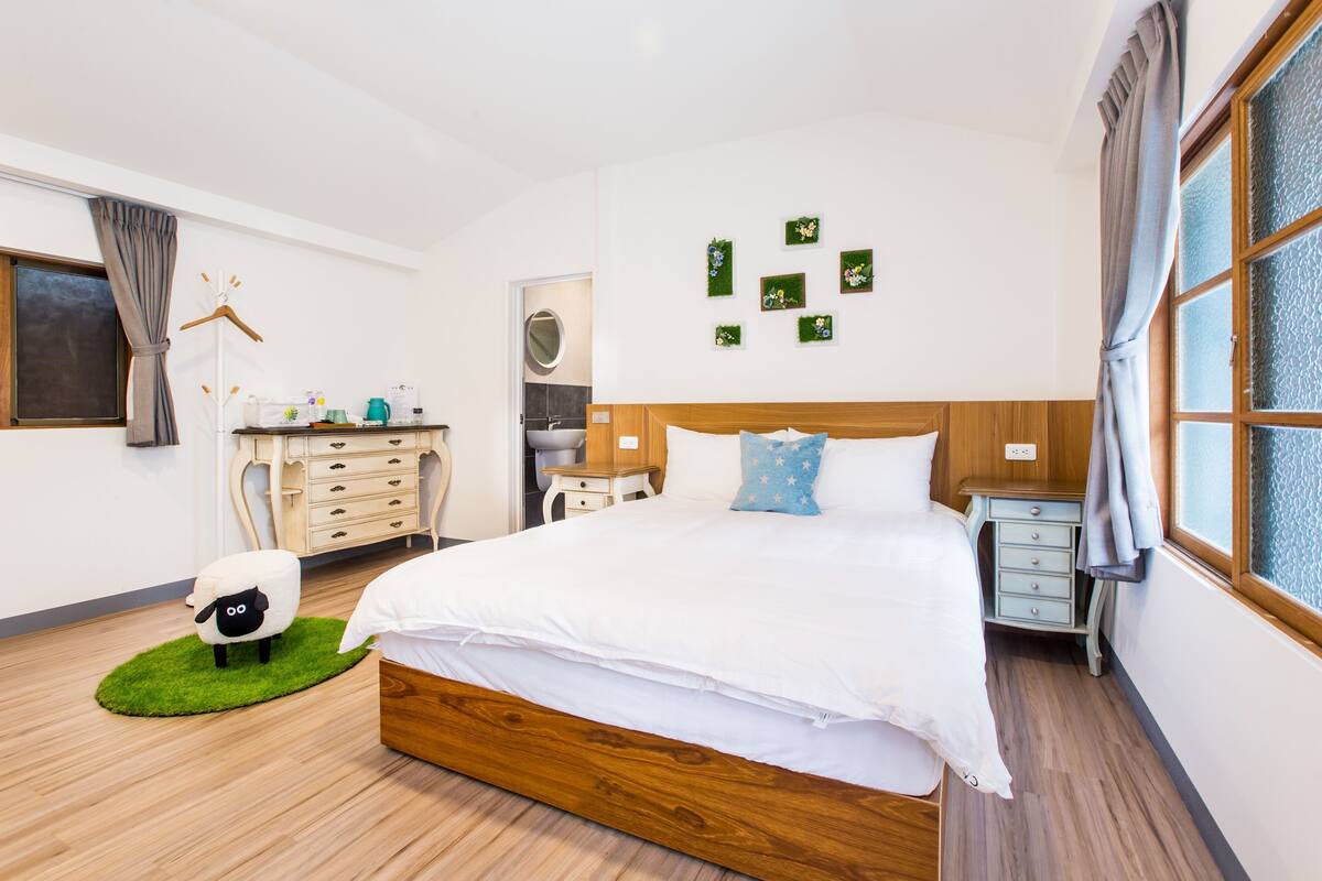 Une chambre à coucher avec un lit en bois, une commode, une table de chevet, une lampe et un tapis vert.