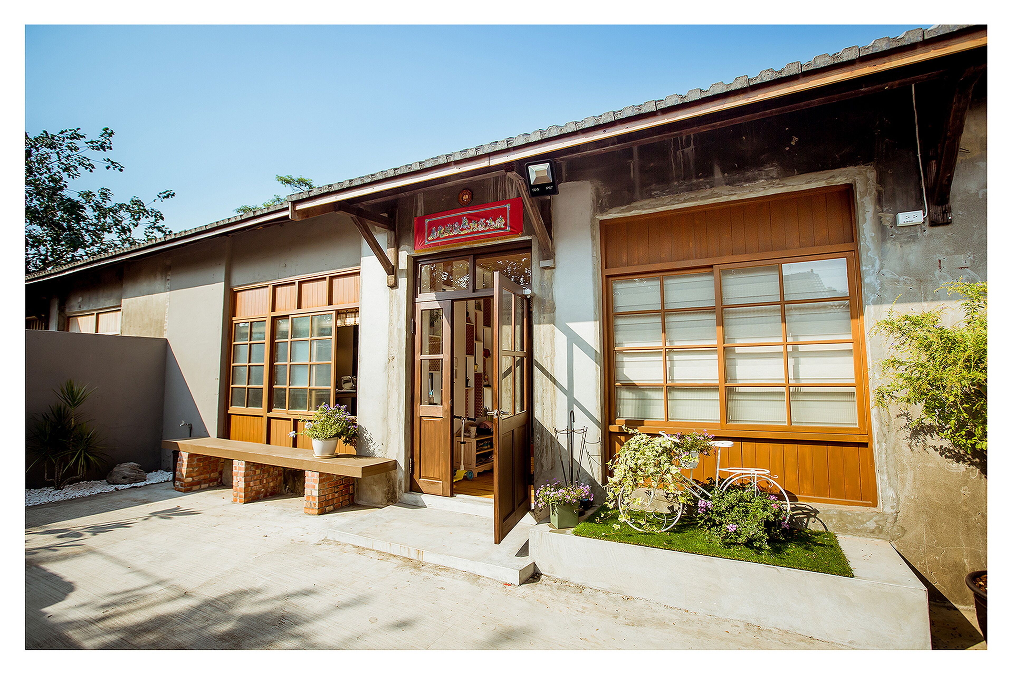A building with a wooden door, a bench, and a sign above the door.