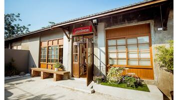 A building with a wooden door, a bench, and a sign above the door.