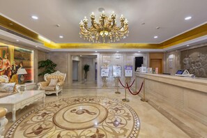 A hotel lobby with a grand chandelier, a reception desk, and a decorative carpet. - Vienna Hotel Shanghai International Tourist Resort Xiuyan Road Metro Station Bra (Shanghai)