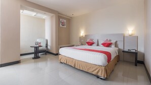 Une chambre d’hôtel avec un grand lit, une table de chevet, une chaise et une petite table avec une autre chaise.