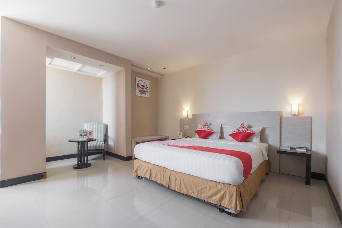 Une chambre d’hôtel avec un grand lit, une table de chevet, une chaise et une petite table avec une autre chaise.
