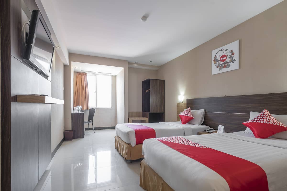 Une chambre d’hôtel avec deux lits, une télévision, une armoire, un bureau et une fenêtre avec des rideaux.