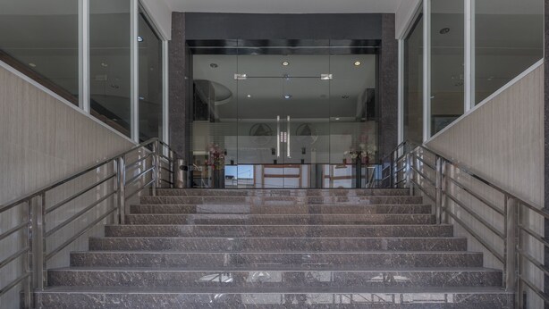 Un intérieur moderne avec un escalier en marbre menant à un espace d’accueil.
