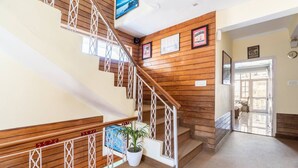 Una escalera de madera con barandillas blancas, una planta en maceta e imágenes enmarcadas en las paredes.