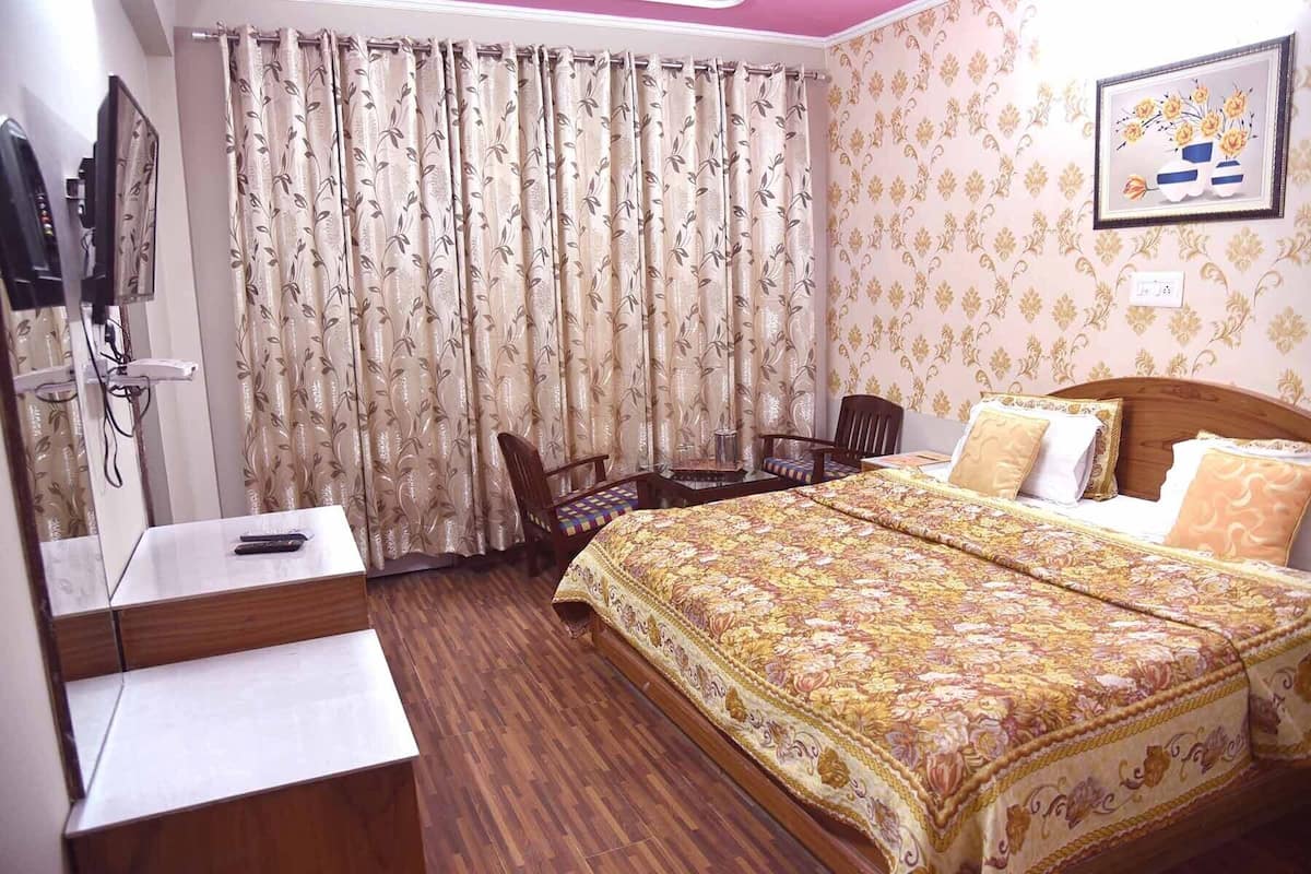 Une chambre d’hôtel avec un lit, un bureau, une chaise, une télévision et des rideaux.