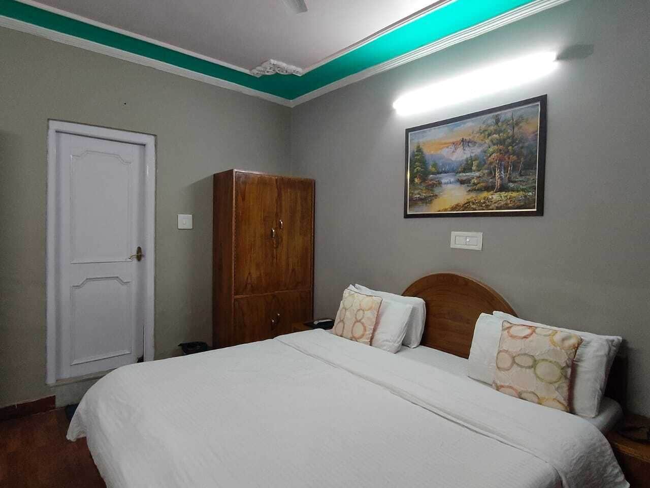 A bedroom with a bed, a wardrobe, and a painting on the wall.