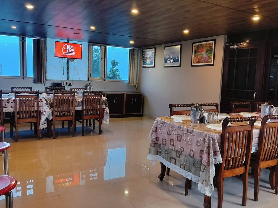 A dining area with wooden tables and chairs, a large window with a view, and a television mounted on the wall.
