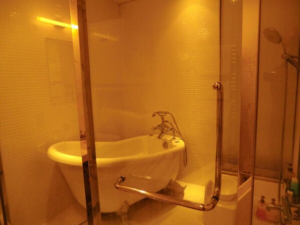 Une salle de bain avec une baignoire blanche, une douche en verre et un lavabo blanc.