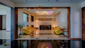 A modern lobby with a glass partition, a chandelier, and a reception desk. - Crescent Spa And Resorts Indore (Indore)