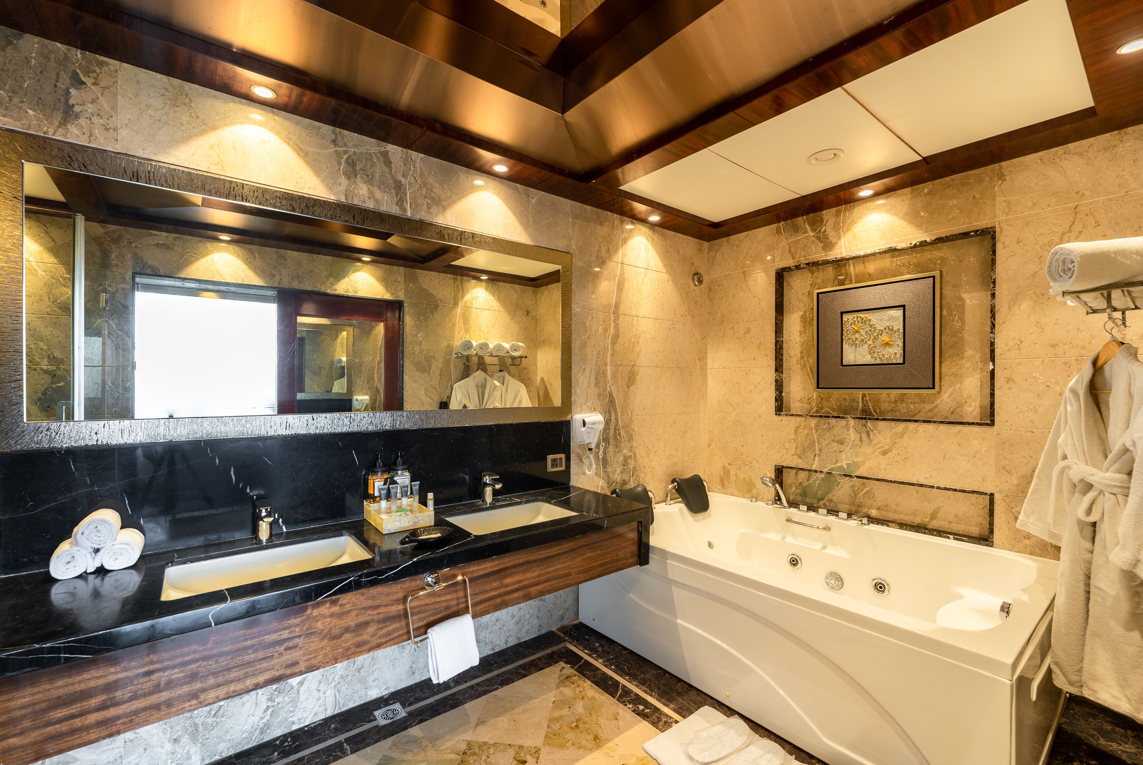 Ein modernes Badezimmer mit einem großen Spiegel, zwei Waschbecken, einer Badewanne und einem Handtuchhalter.