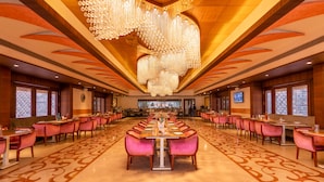A spacious hotel dining area with a long table set for a banquet, surrounded by pink upholstered chairs. - Crescent Spa And Resorts Indore (Indore)