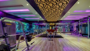 A gym with various exercise equipment, wooden flooring, and purple lighting. - Crescent Spa And Resorts Indore (Indore)