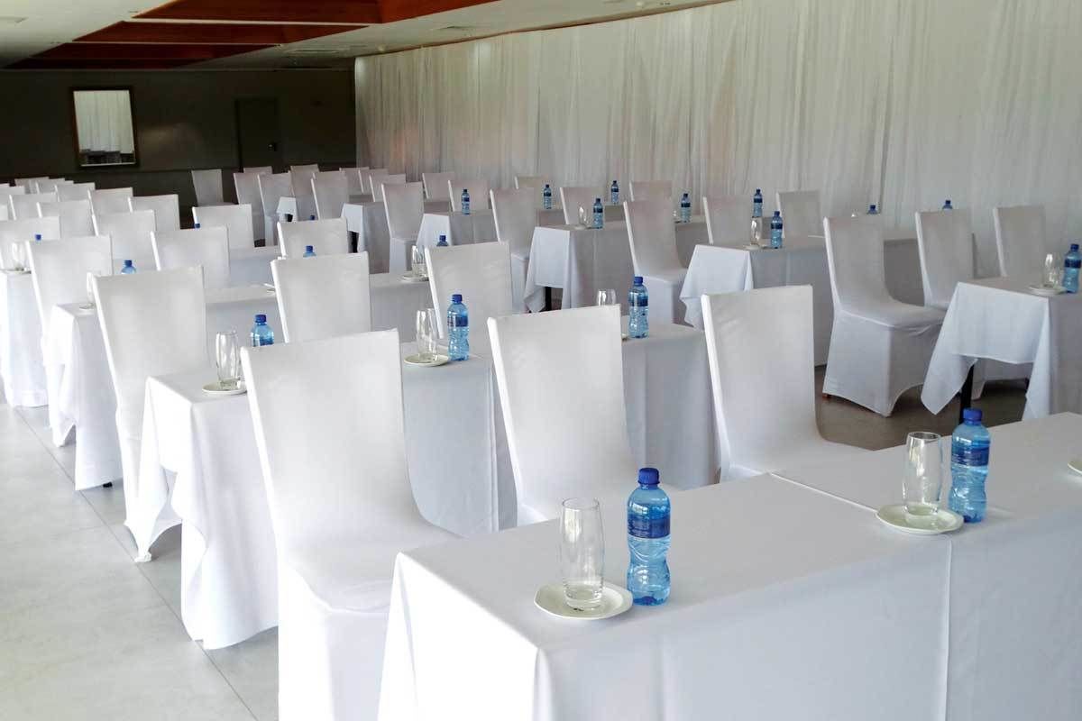 Una sala de banquet amb files de taules, cadascuna coberta amb estovols blancs, cadieres i amples d'aigua.