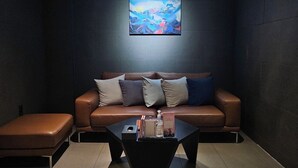 A modern room with a brown leather sofa, a black coffee table, and a painting on the wall. - Rivertain Hotel Gyeongju (Gyeongju)