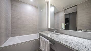 Un baño moderno con bañera, un espejo grande y encimera de granito.