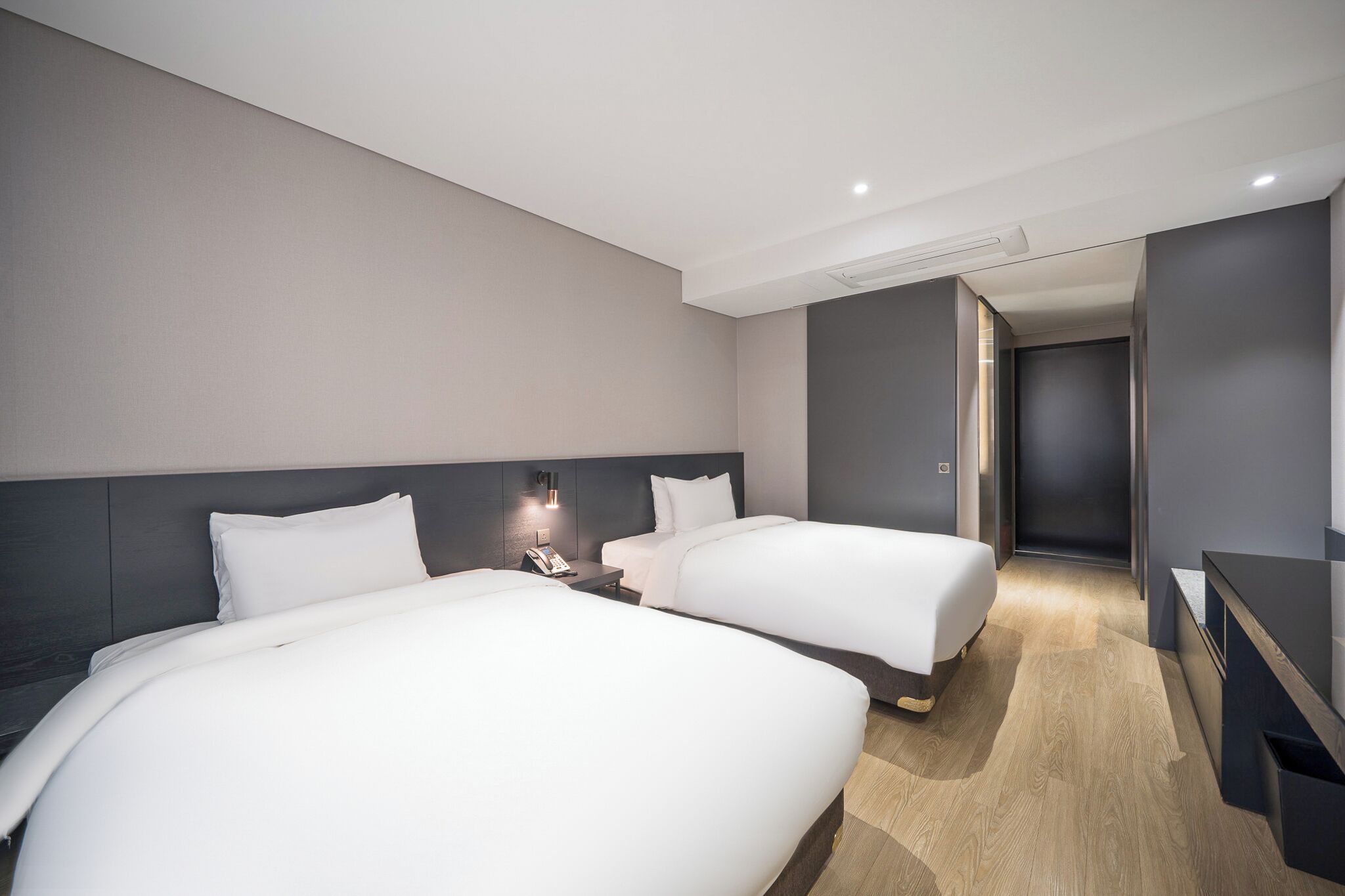 A hotel room with two beds, a desk, and a walk-in closet.