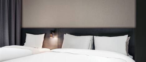A neatly made bed with white linens and a dark headboard.