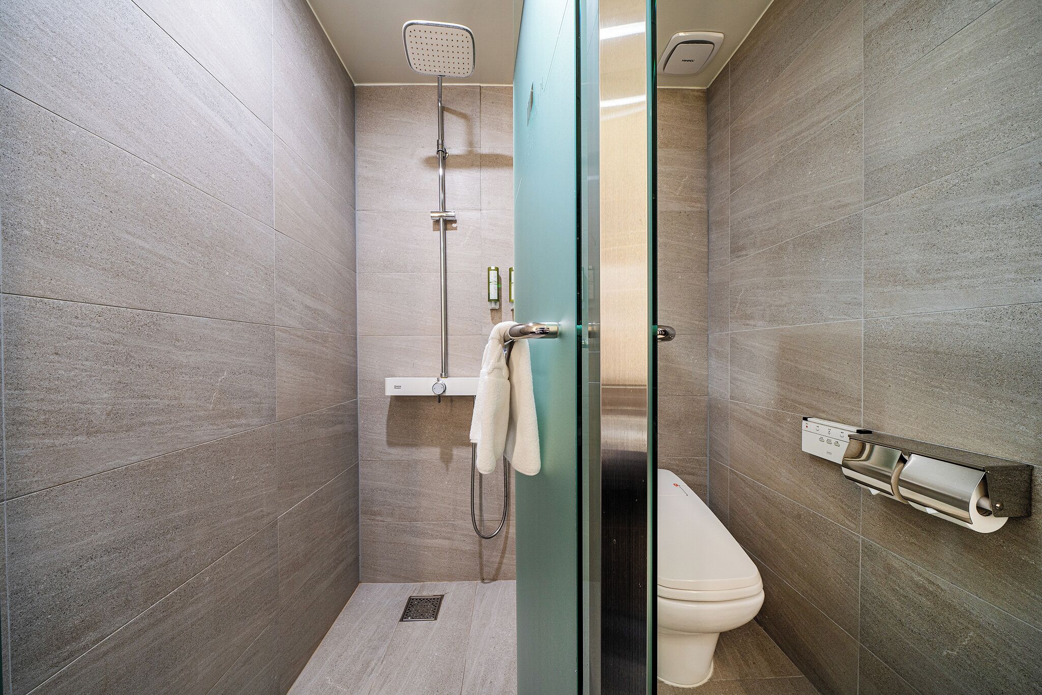 A modern bathroom with a glass shower enclosure, a toilet, and a towel rack.