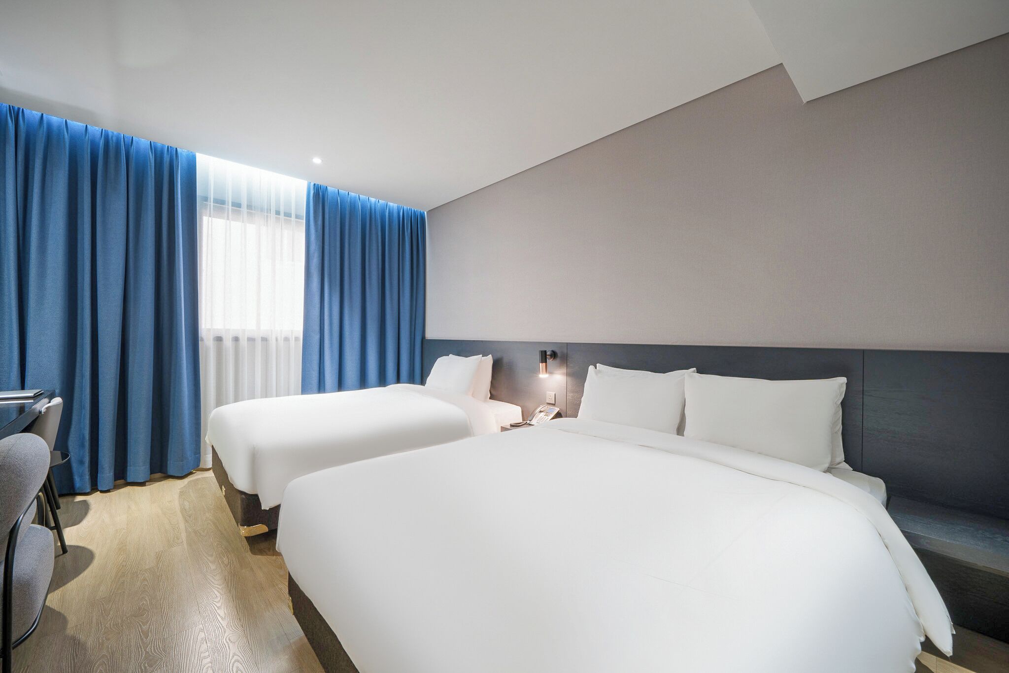Habitación de hotel con dos camas, un escritorio y una silla.