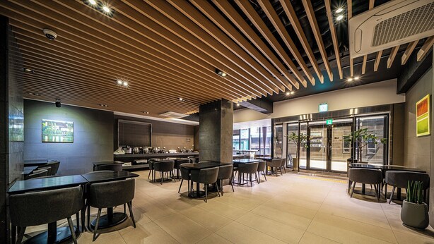 A modern restaurant with a wooden ceiling, black tables, and chairs. - Rivertain Hotel Gyeongju (Gyeongju)