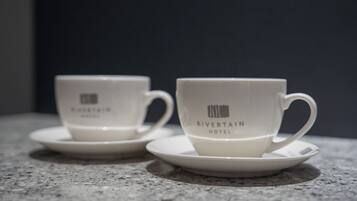 Two white cups with the Rivertain Hotel logo on a granite countertop.