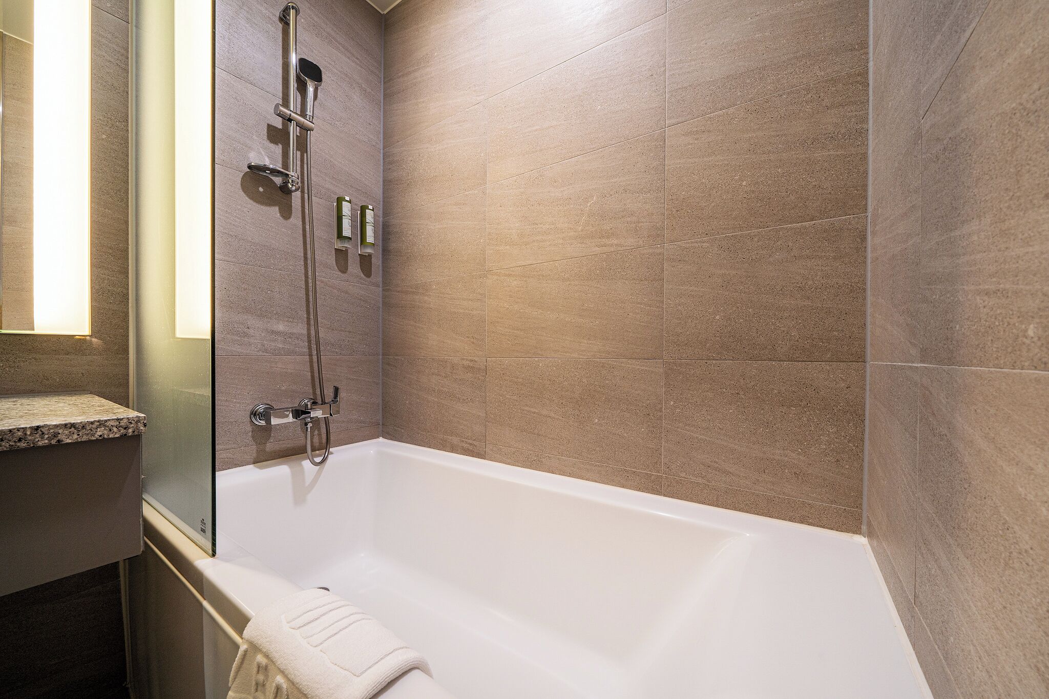 Een moderne badkamer met een bad, douche en een wastafel met glazen afscheiding.