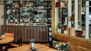 A restaurant with a wooden counter, shelves with various items, and a seating area with a table and chairs. - Vienna House Kronberg (Kronberg)