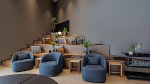 A modern living room with a staircase, seating area, and a TV mounted on the wall. - Vienna House Kronberg (Kronberg)