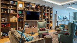 Un salon moderne doté d’un grand téléviseur à écran plat, de nombreuses étagères et de sièges confortables.