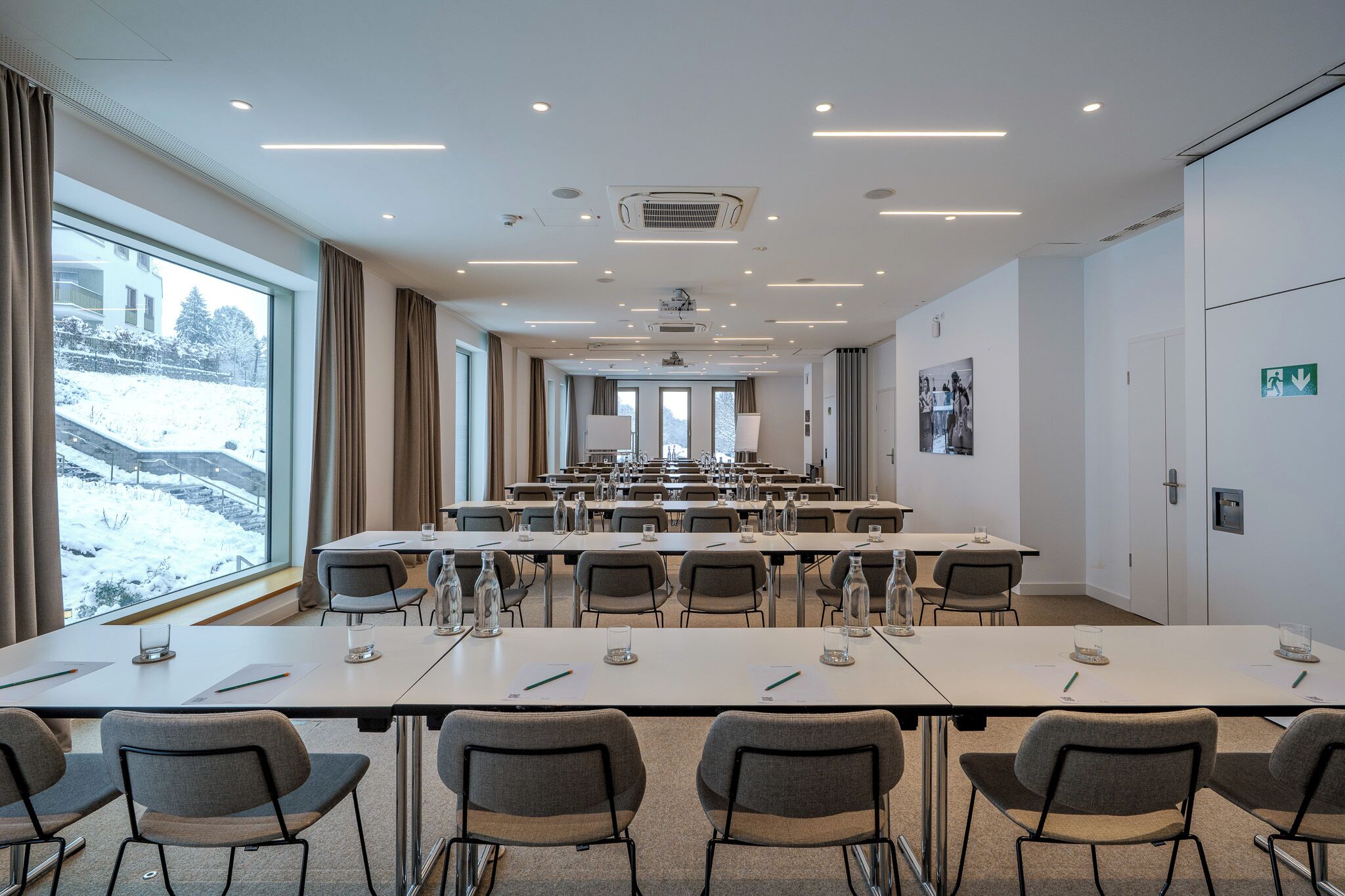 A conference room with tables, chairs, and a large window with a view of snow-covered landscape.