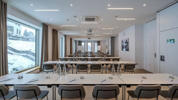 A conference room with tables, chairs, and a large window with a view of snow-covered landscape.