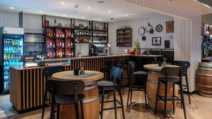 Un espace bar avec des comptoirs en bois, des tabourets et des étagères remplies de bouteilles.