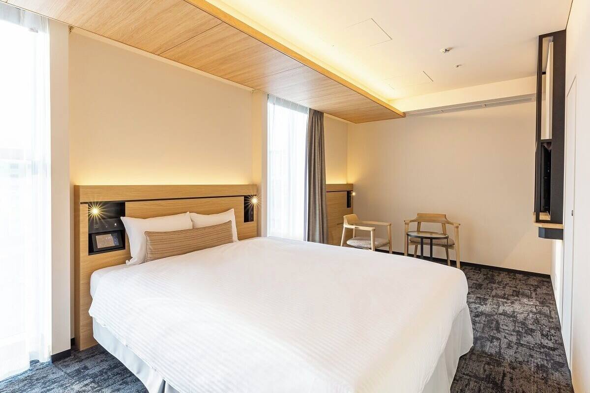 A hotel room with a large bed, a desk, and a chair.