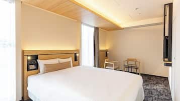 A hotel room with a large bed, a desk, and a chair.