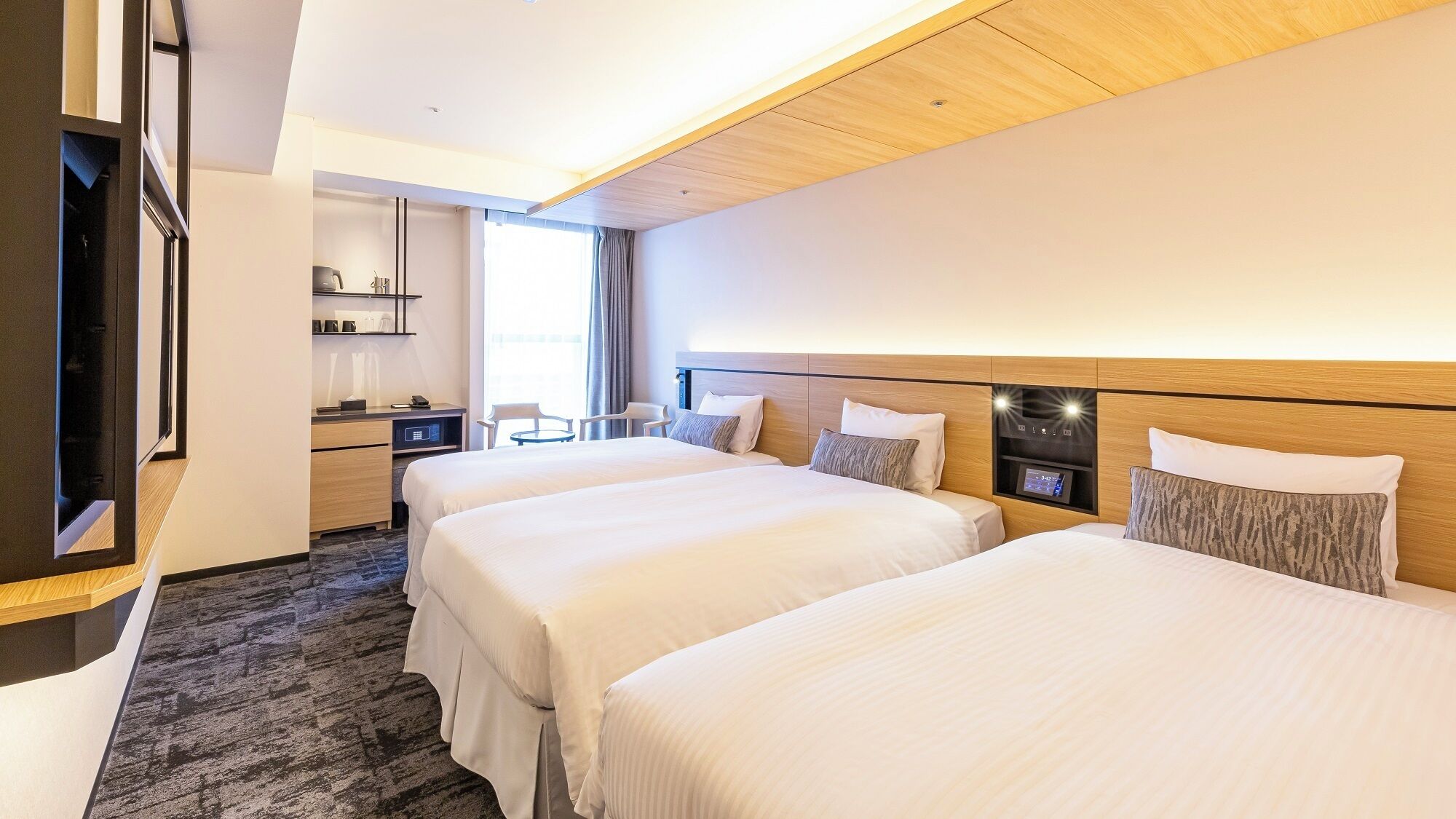 Habitación de hotel con dos camas, un escritorio, una silla y un televisor.