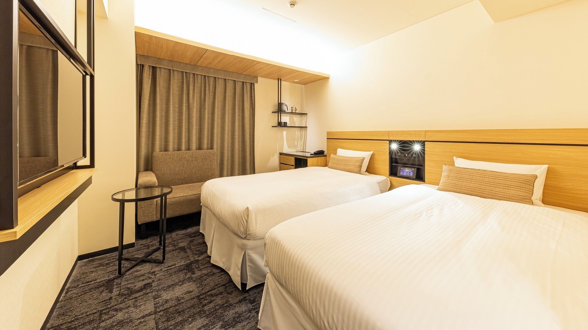 Una habitación de hotel con dos camas, una mesita, un sofá y un televisor.