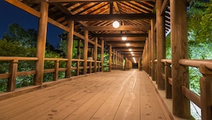 A wooden covered walkway with railings, leading to a forested area. - Hotel Keihan Kyotoeki Minami (Kyoto)